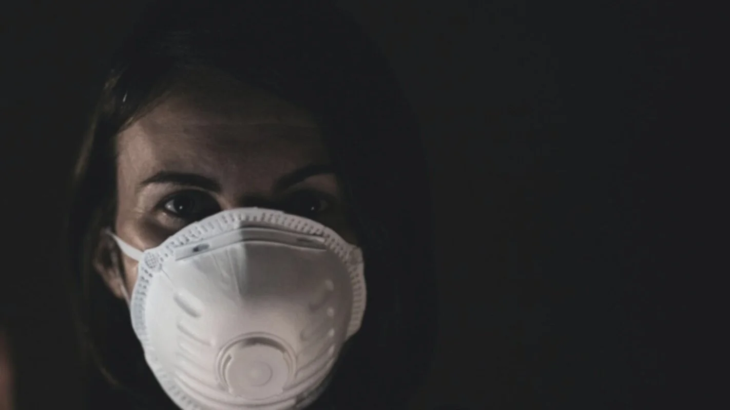 Two workers comparing respirator use in a workshop, one required and one voluntary