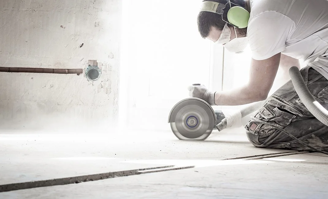 Worker performing dust-controlled concrete cutting under OSHA silica standard requirements