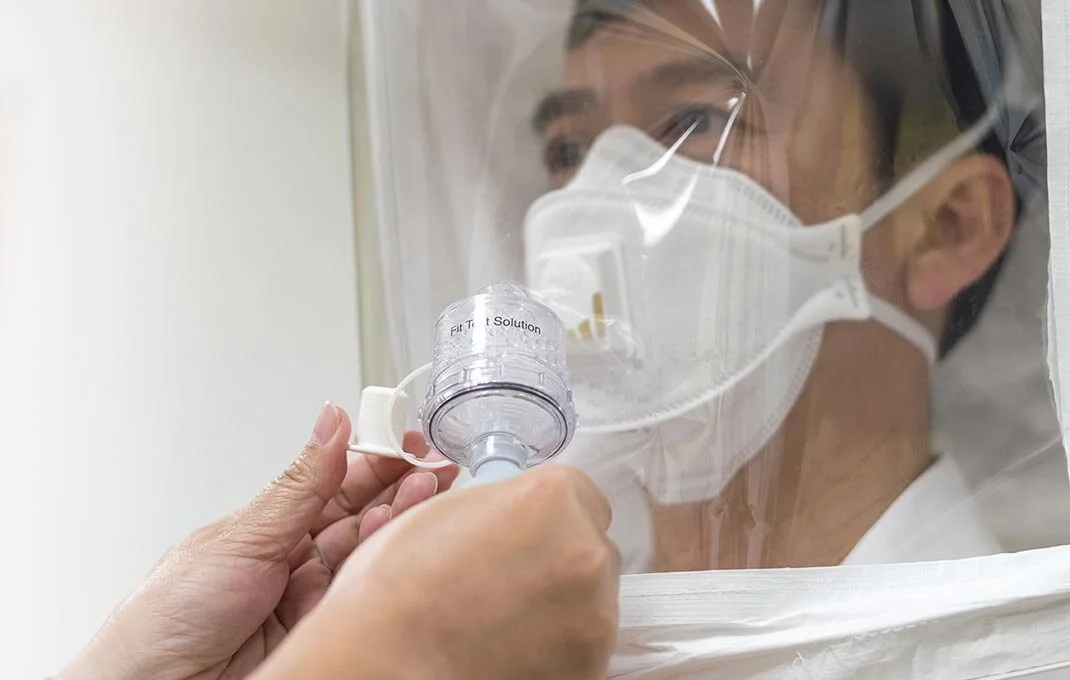 Safety professional performing a qualitative respirator fit test on a worker wearing an N95